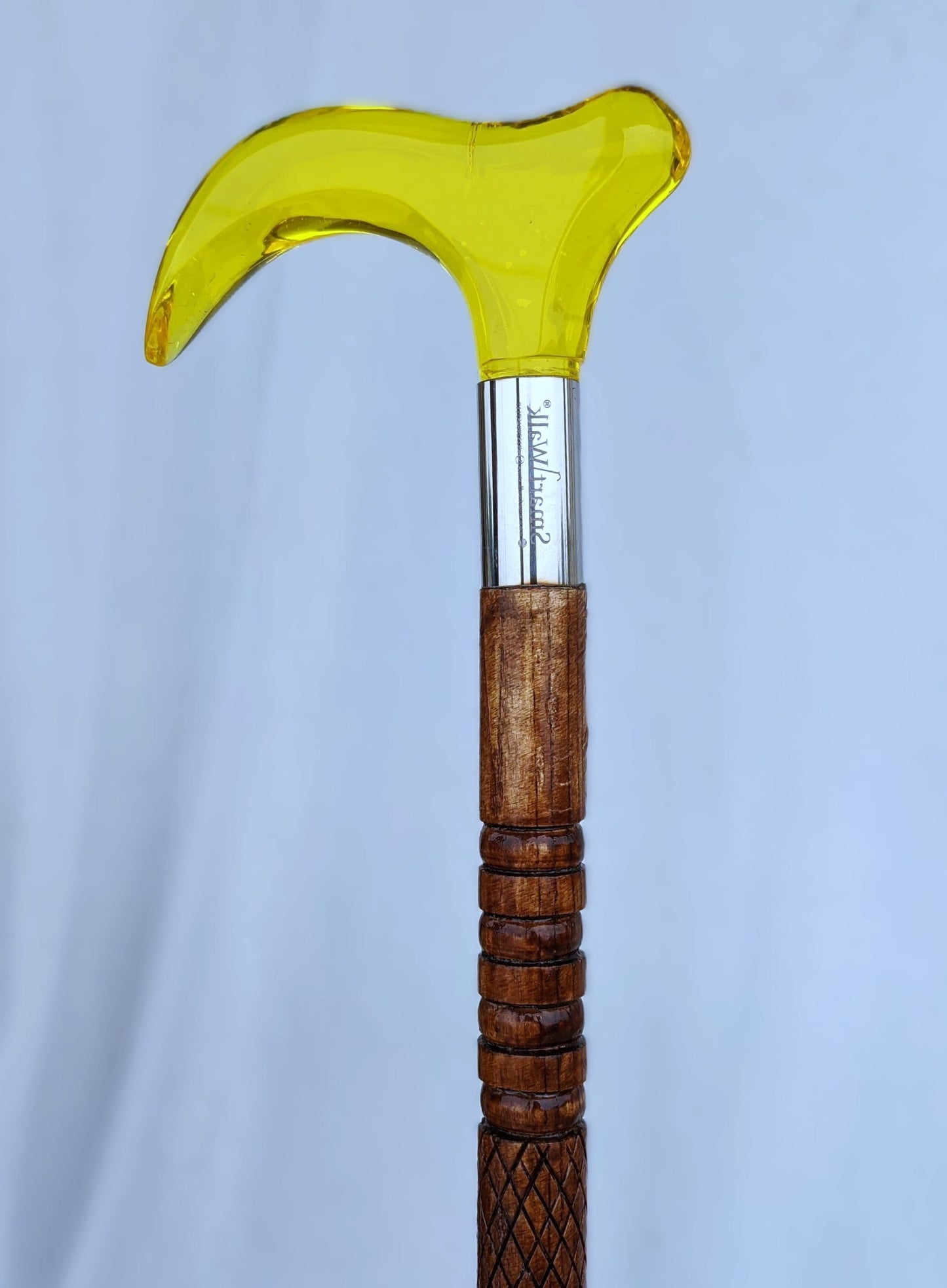 Wooden walking cane with a yellow glass handle on a light blue background